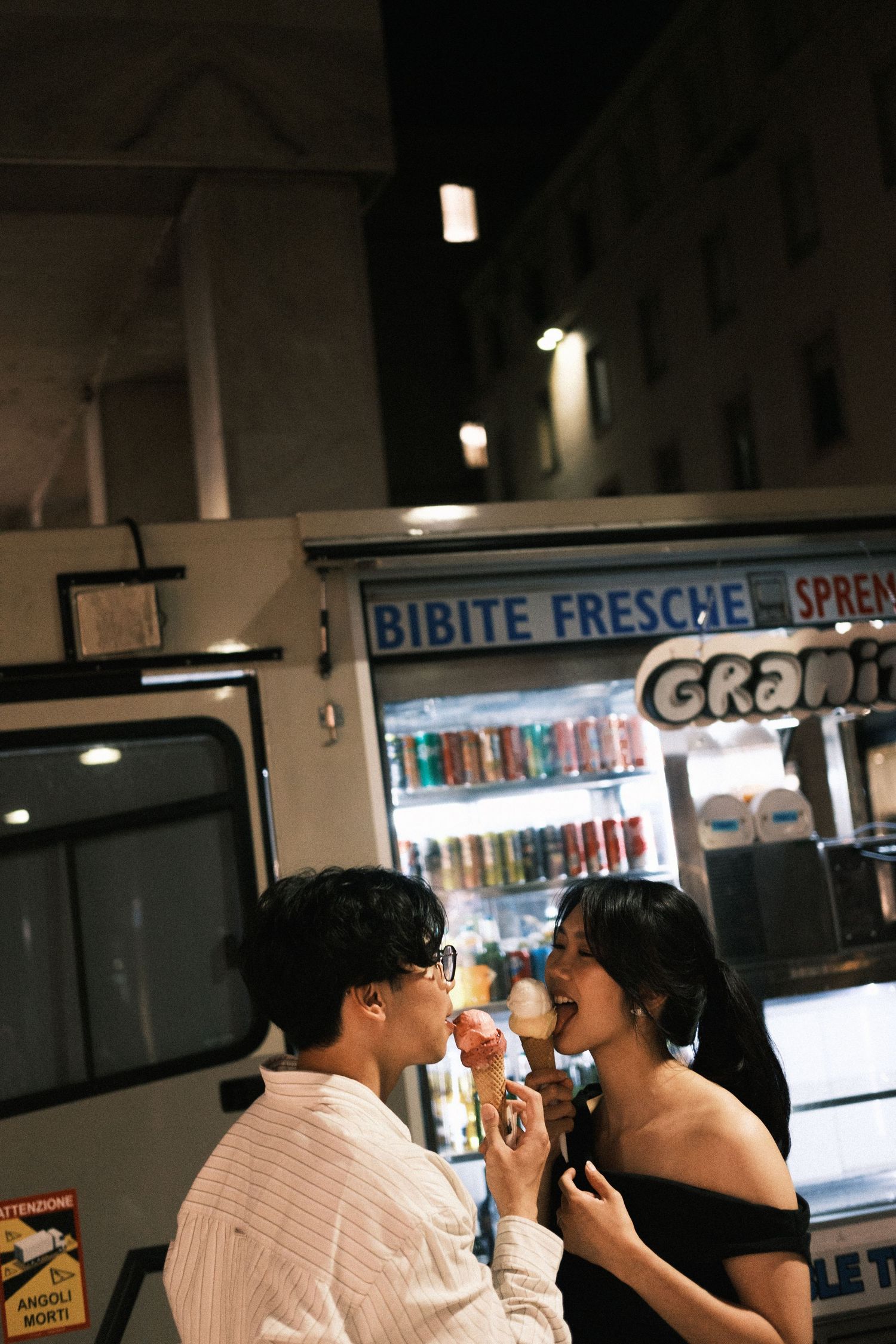 Two people share a casual meal together at a casual restaurant counter with illuminated beverage displays in the background.