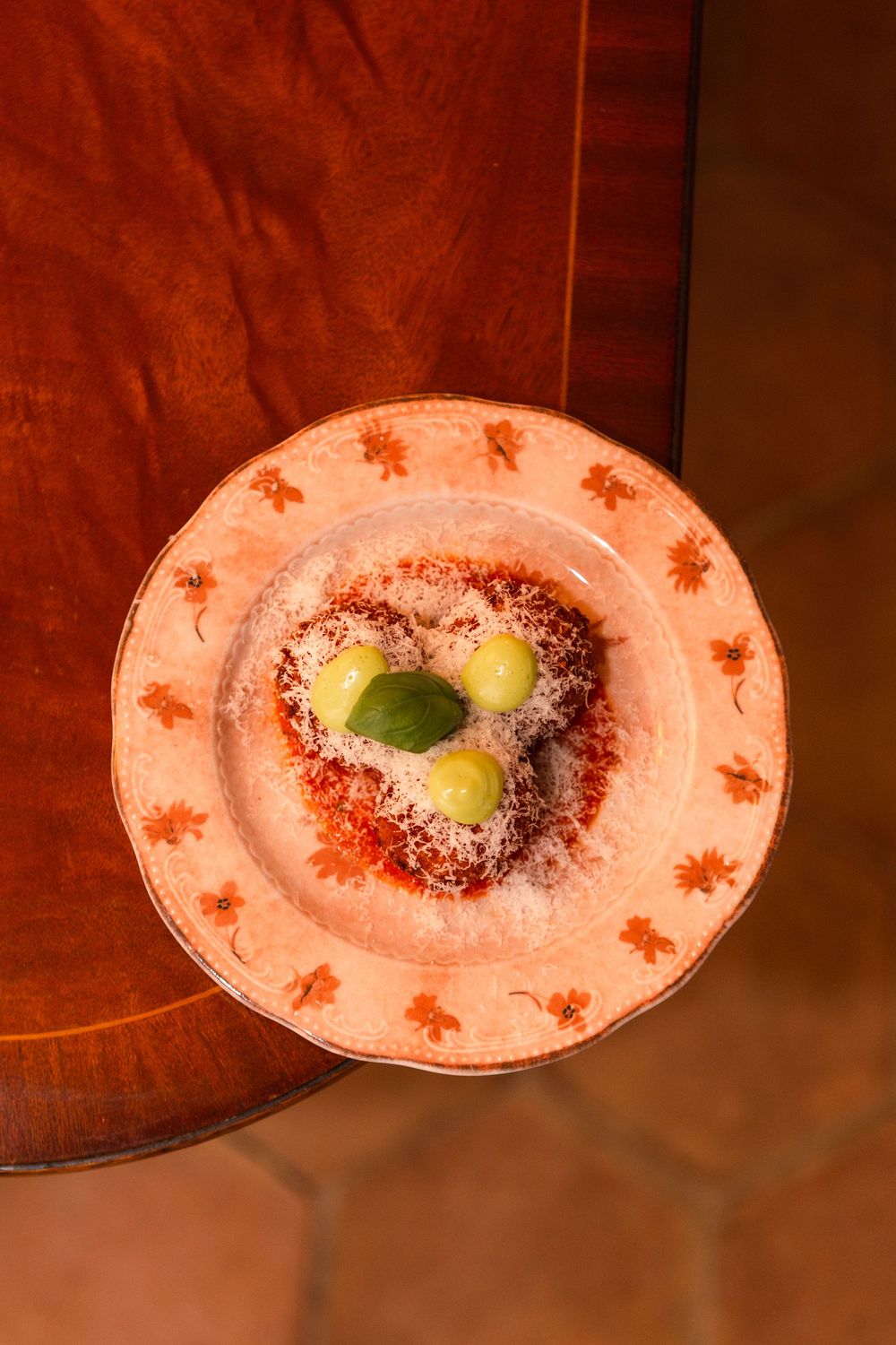 Three elegant dessert plates with chocolate and lime garnish on a dark wooden table in warm lighting.