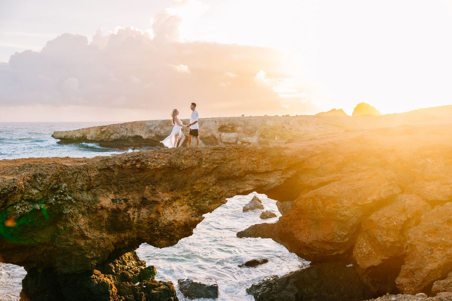 Dramatic sunset wedding photography on rocky coastal cliffs overlooking the ocean.