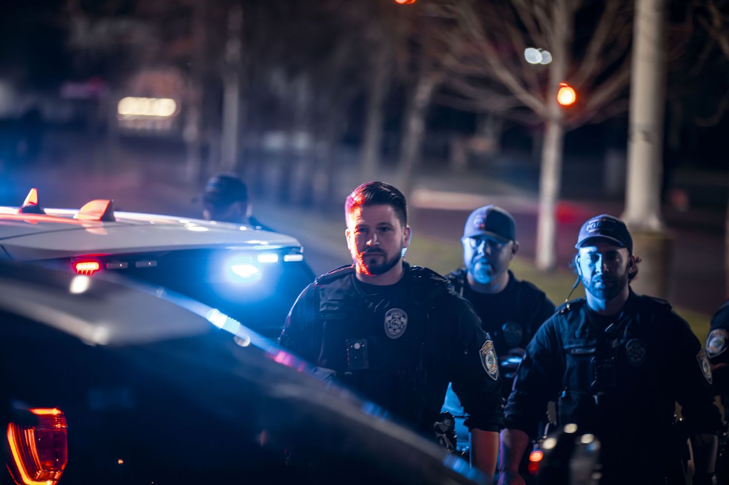 Emergency vehicles with flashing lights illuminating nighttime scene.