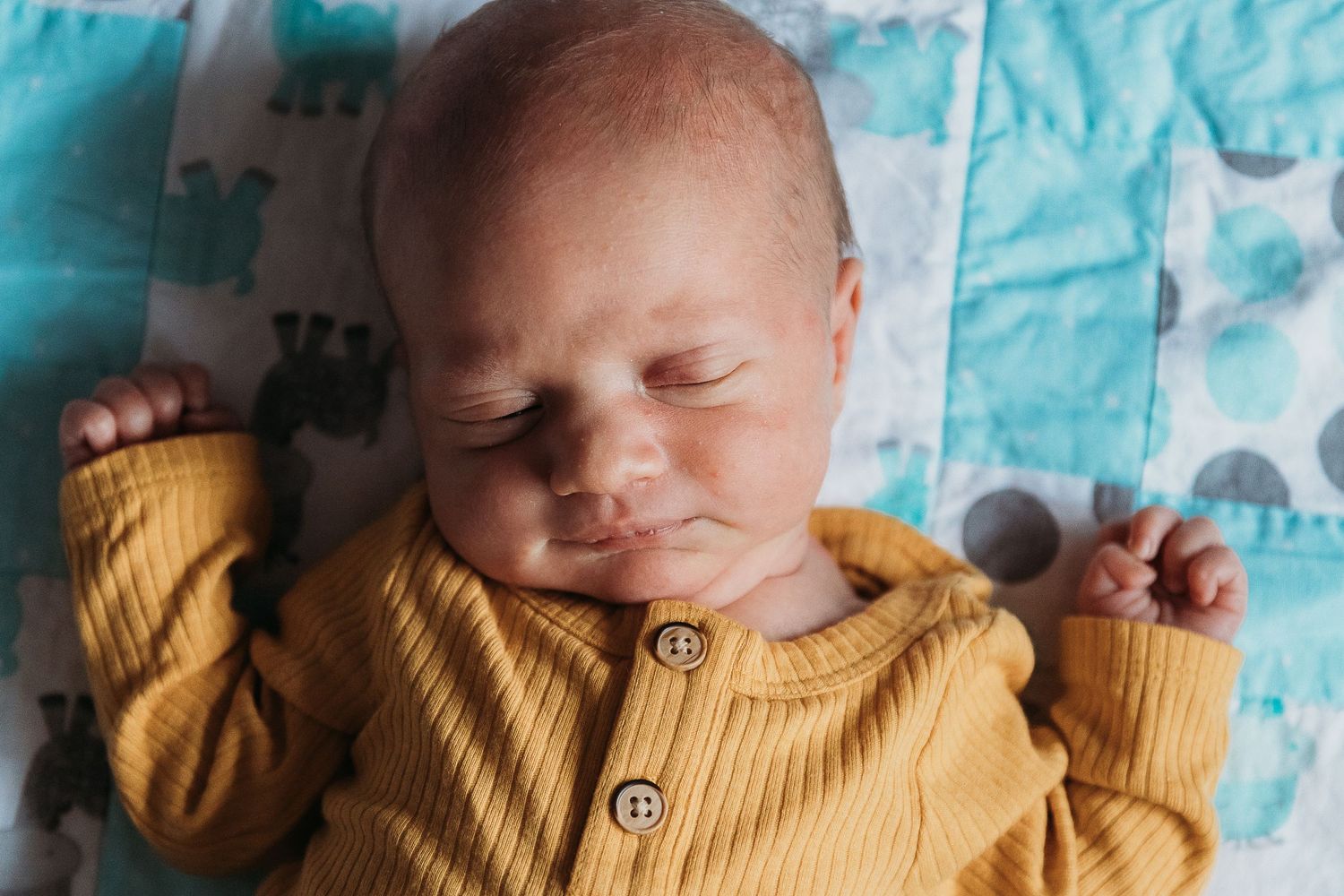 Collage of baby sleeping peacefully in yellow sweater against blue patterned background.