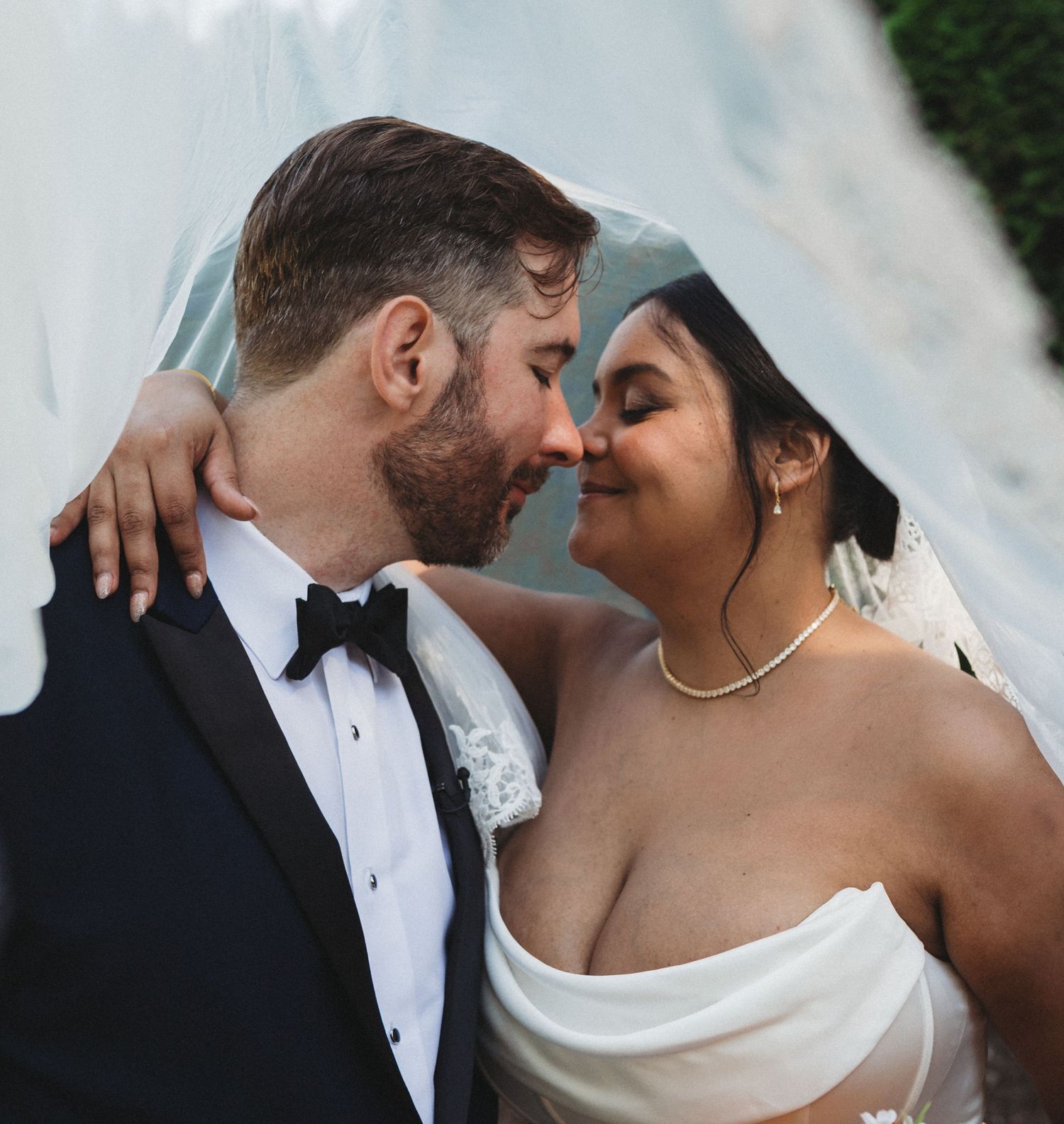 Intimate moment between newlyweds sharing a romantic pose under a veil.