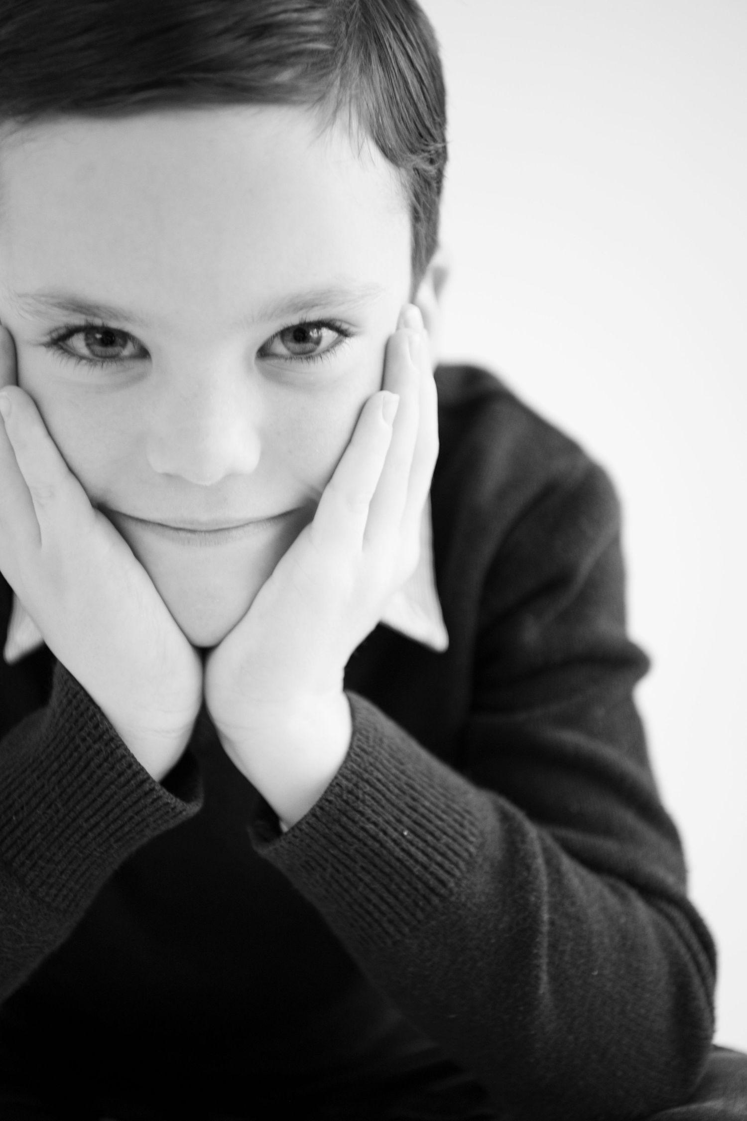 A series of black and white photos showing a person resting their chin on their hands while wearing a dark sweater.