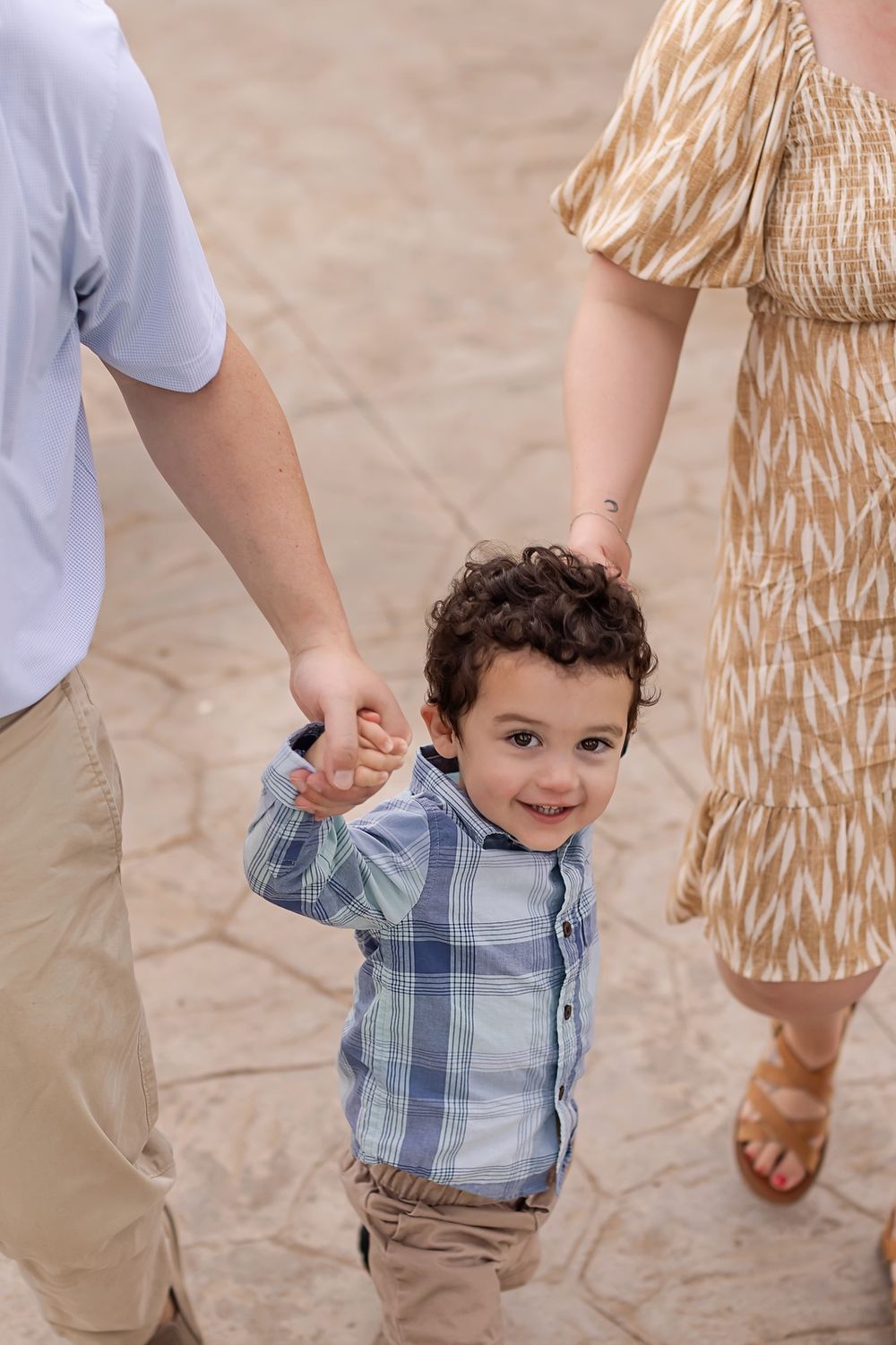 Parents holding hands with their child during a family photo session in Mexico.