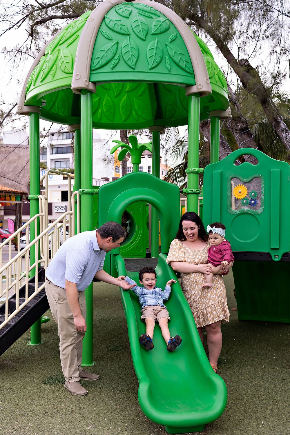 Children playing on a green slide during a family photo session.