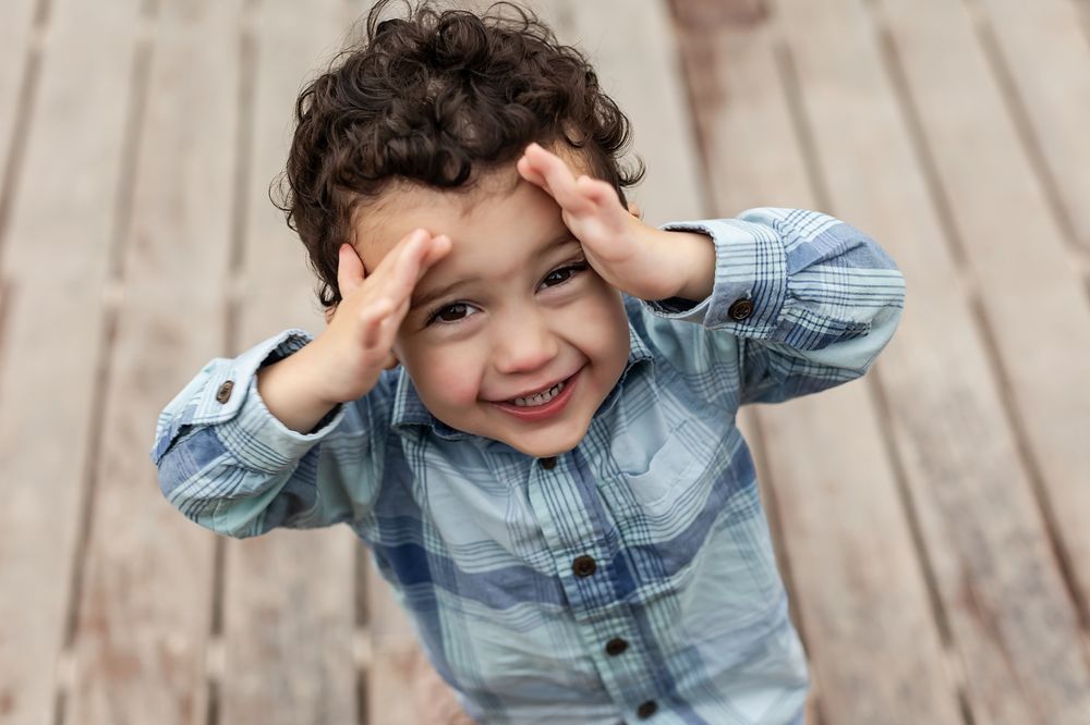A candid moment of laughter and joy captured in front of a wooden wall background.