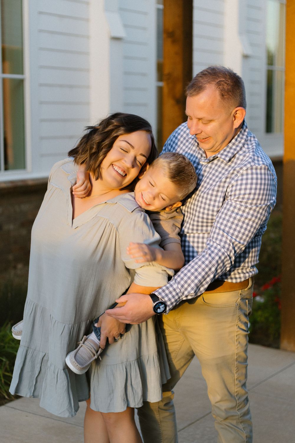 Family embraces in tender moment outside church building during sunset.