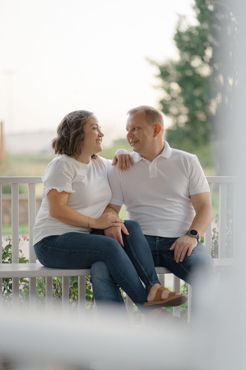Couple shares intimate moment while sitting together on outdoor porch.
