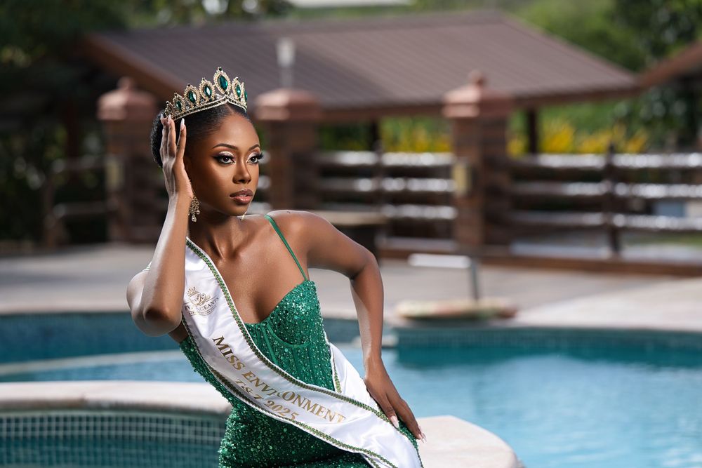 Beauty pageant contestant in emerald green gown poses elegantly by a swimming pool.