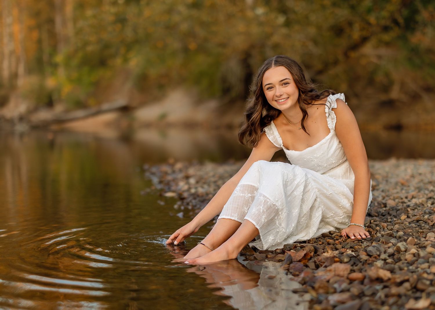 Artistic waterside photography session with natural poses on rocky riverbank.