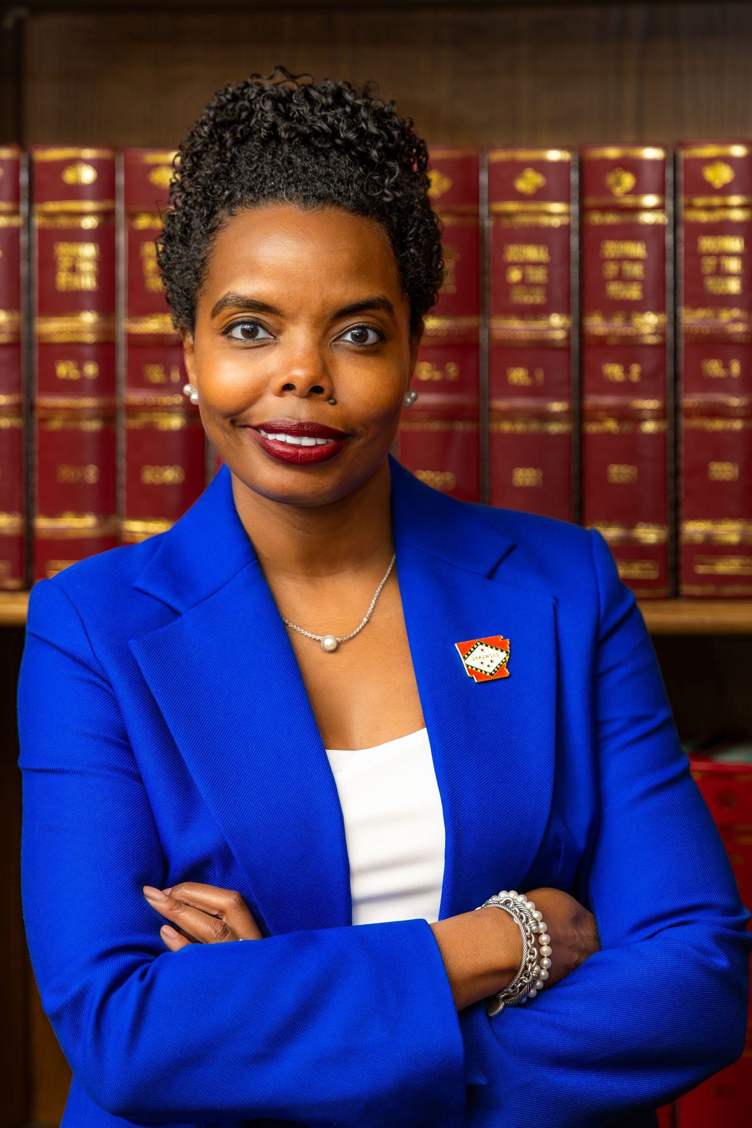 Professional portrait series of a person in a bright blue blazer and white top against a backdrop of law books.