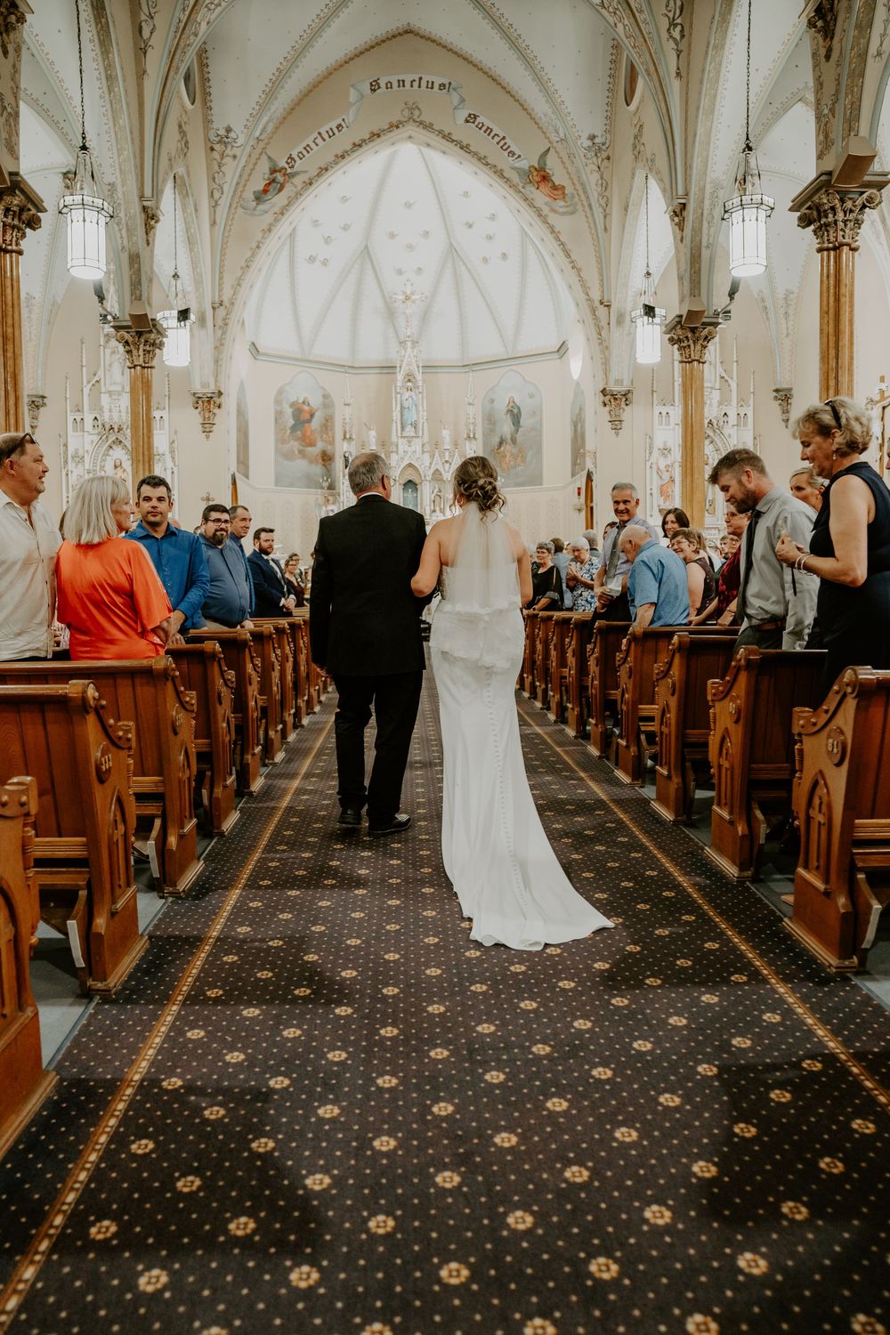 bride and father walk down the aisle back shot