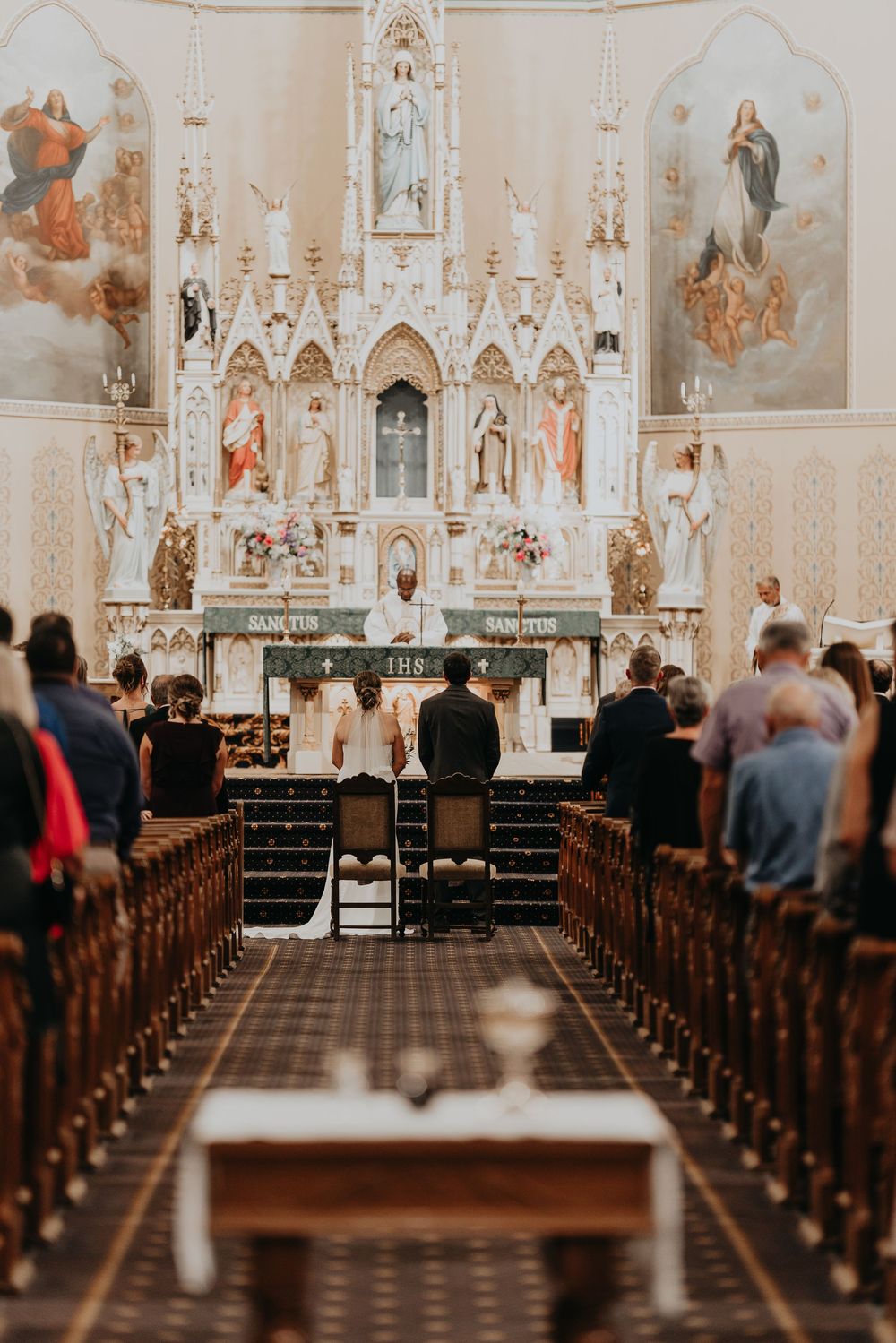 bride and groom seated in front of the alter and in the foreground the sacred vessels stand on a small table