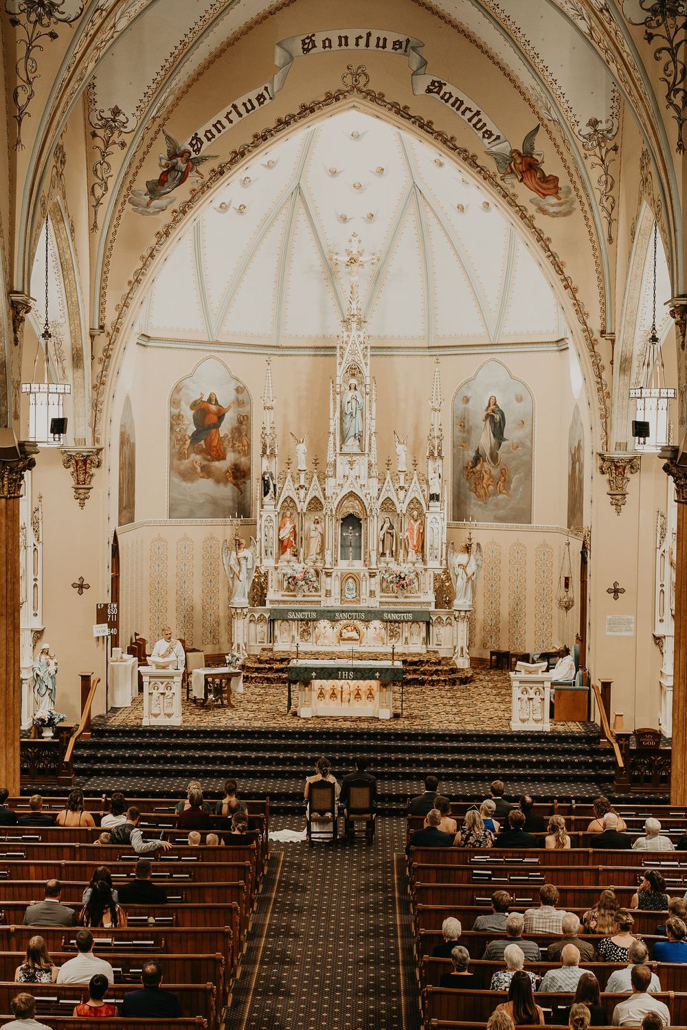 wide shot of church with bride and groom in sitting in front of the altar