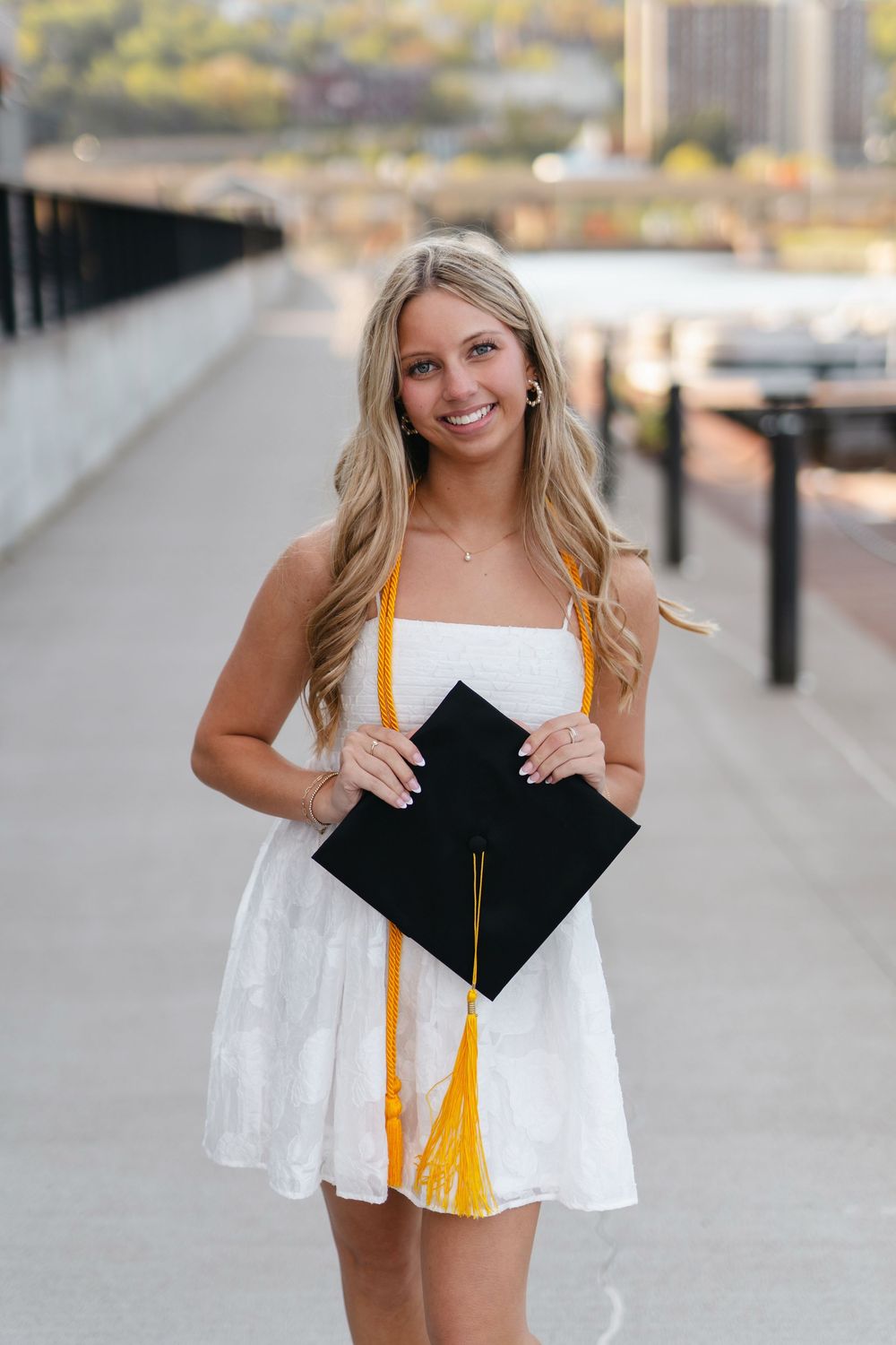 A series of graduation photos showing someone holding a diploma and wearing white against an urban background.