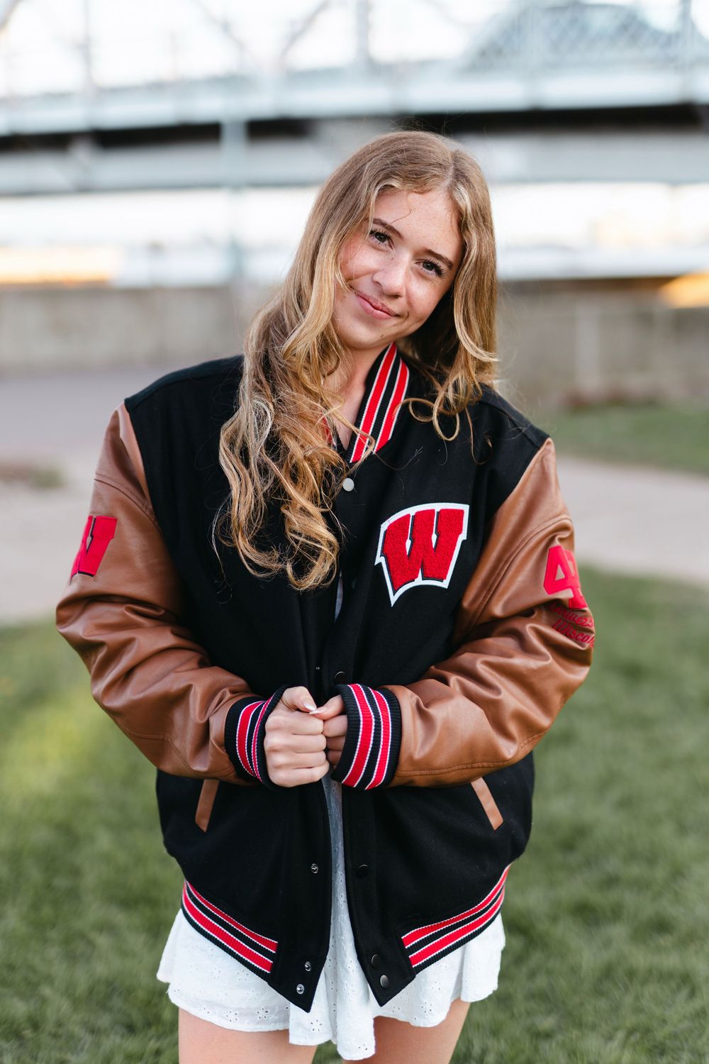 A varsity letterman jacket in black and brown with a Wisconsin 'W' logo is shown from different angles.