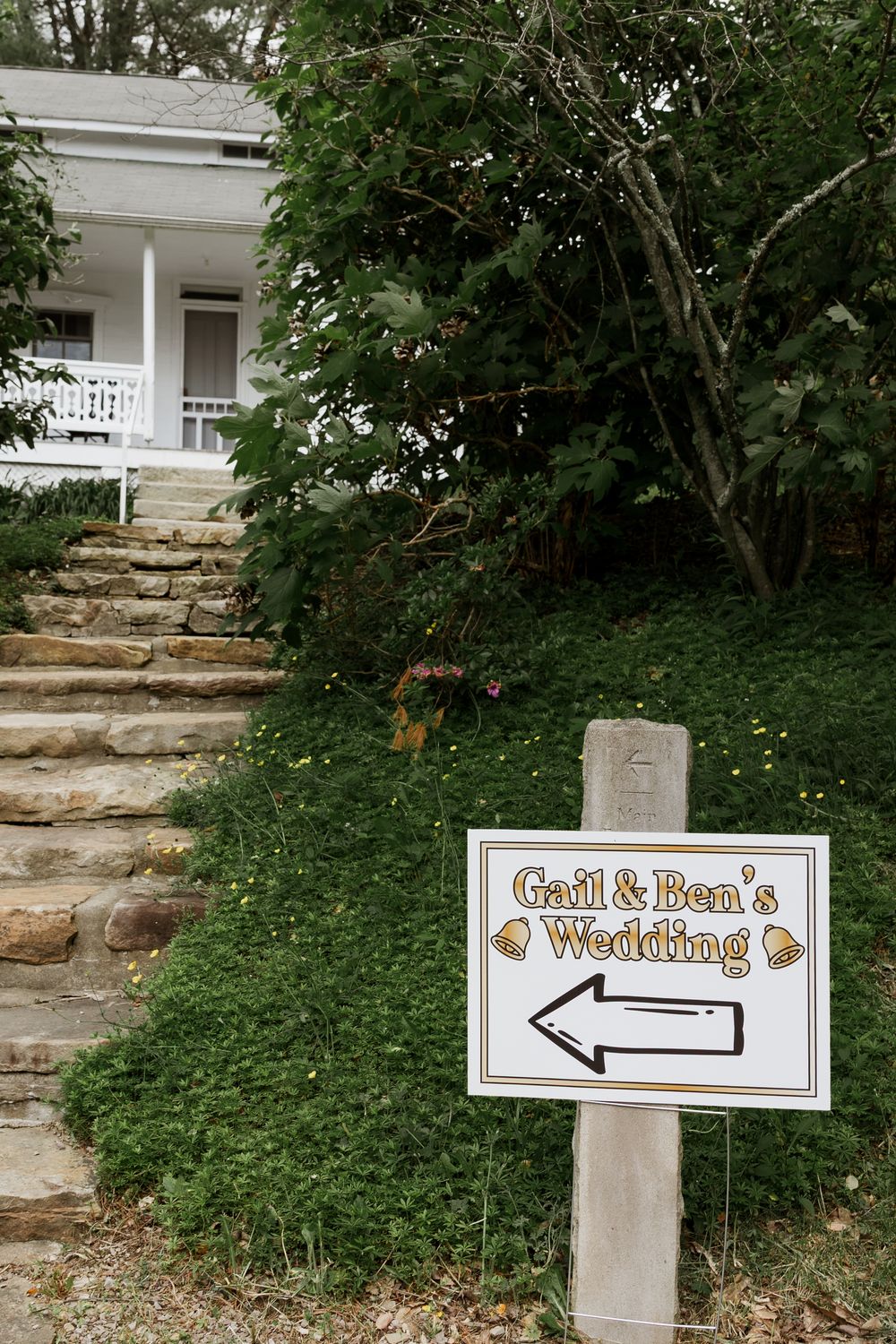 Directional wedding signs with arrows point the way to 'Gail & Ben's' and 'Wedding' on rustic white posts.