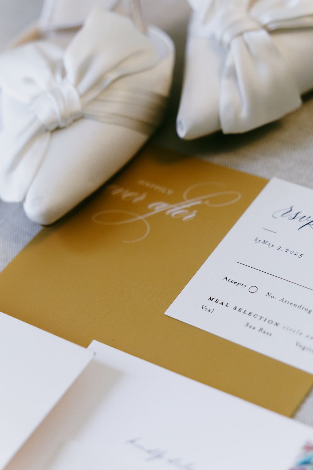 White gloved hands arranging elegant gold and white wedding invitation cards on a table surface.