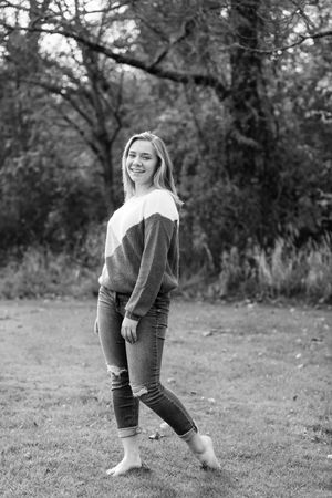 Black and white photos capturing playful poses on grassy ground with natural lighting and trees in background.