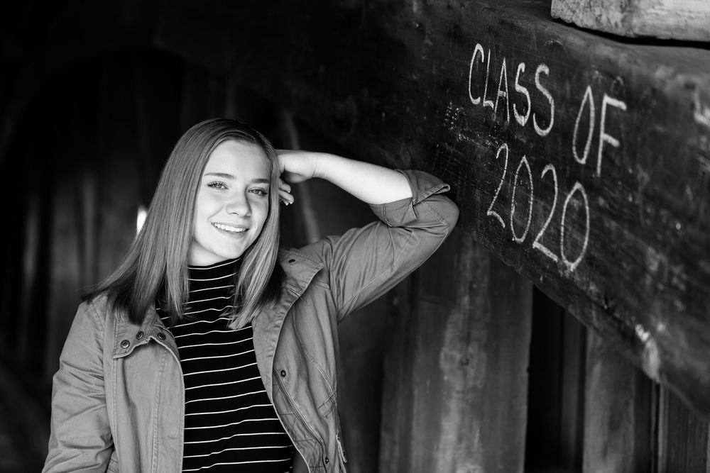 Artistic black and white senior photo shoot against rustic backdrop with graffiti.