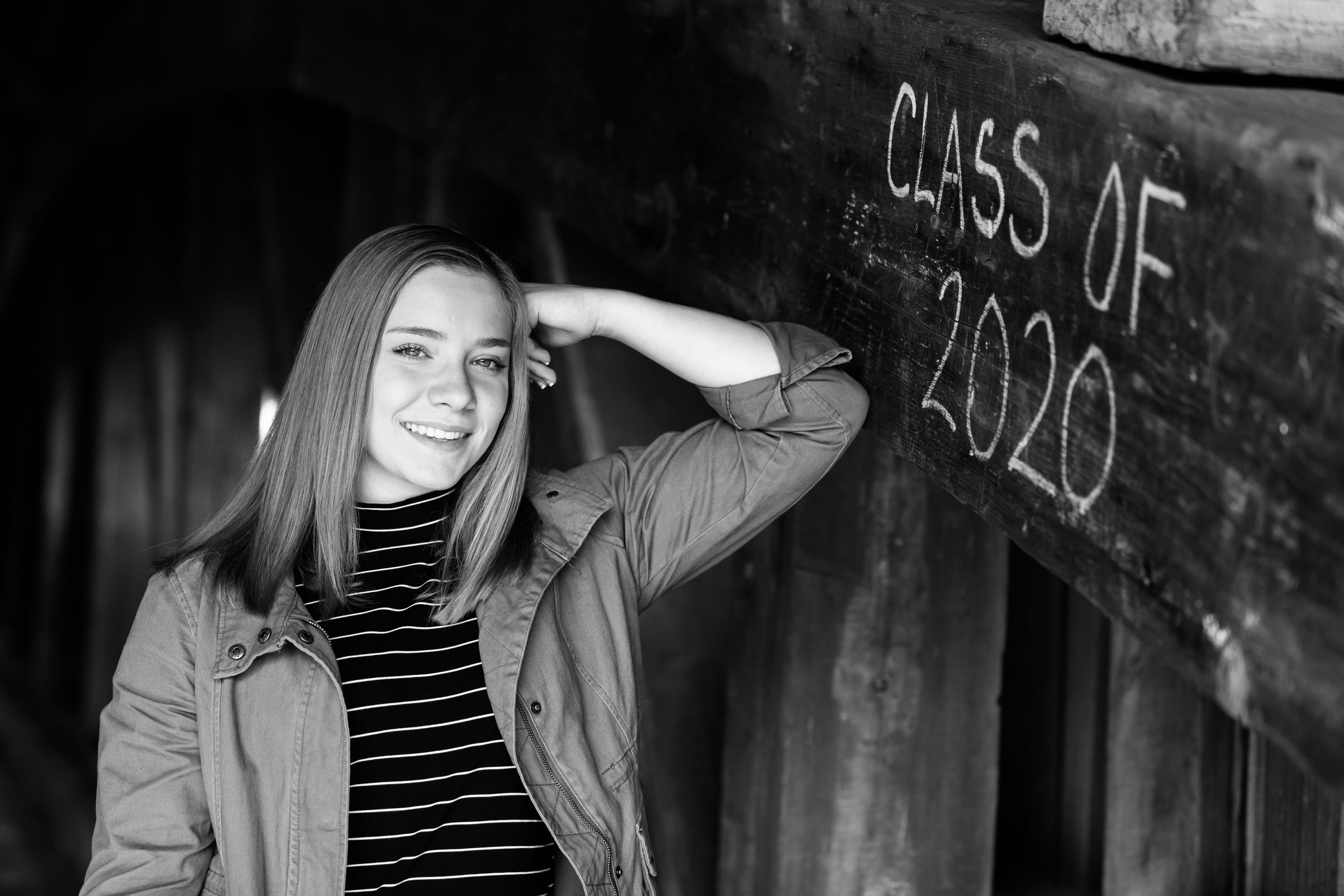 Artistic black and white senior photo shoot against rustic backdrop with graffiti.