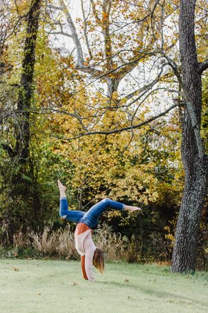 Sequence showing a cartwheel movement in a grassy field with autumn trees in the background.