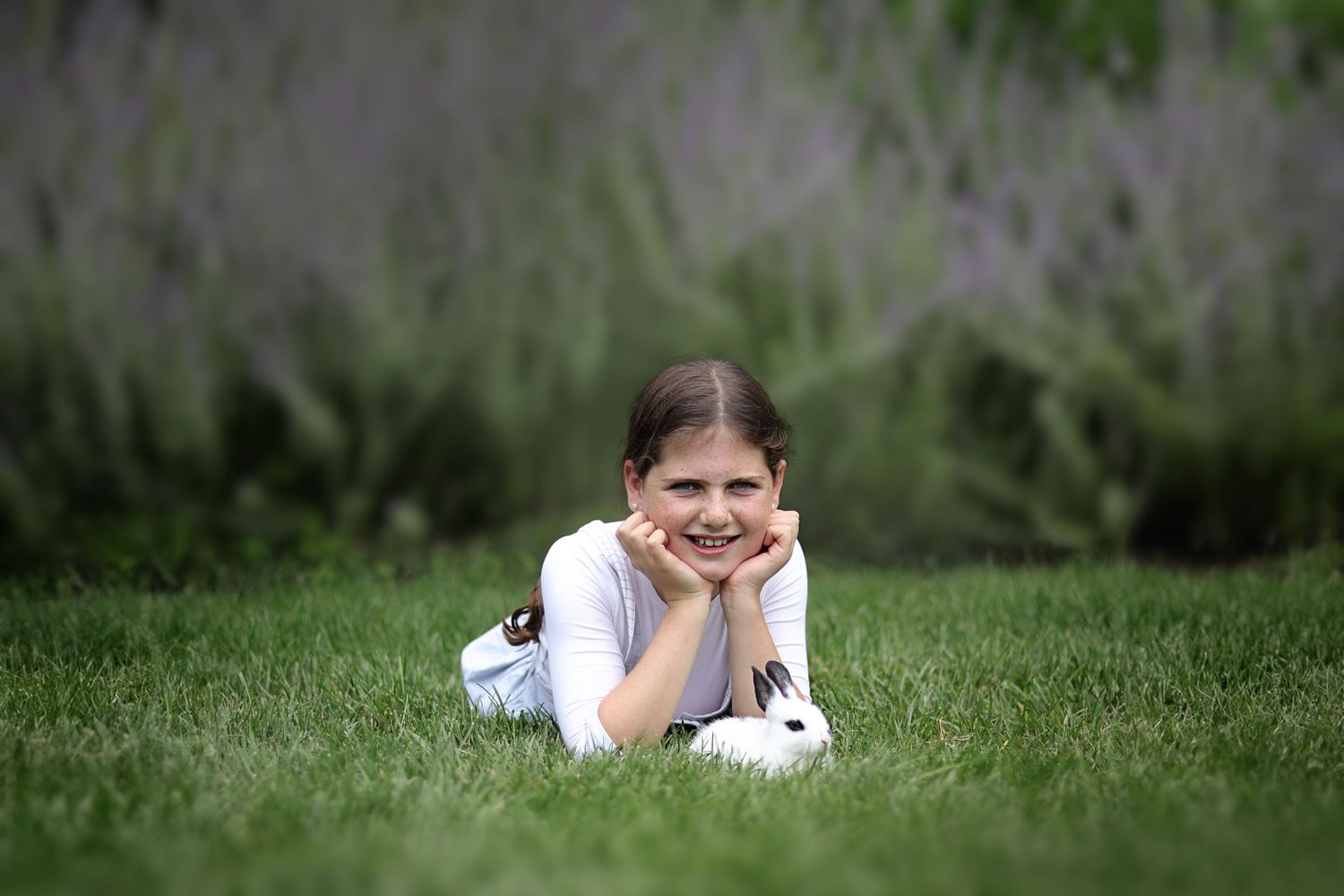photo of young girl lying in the grass with her pet bunny