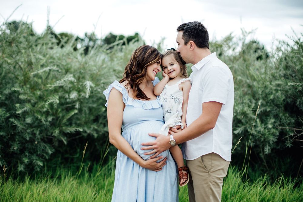 Family sharing tender moment together in outdoor field setting.