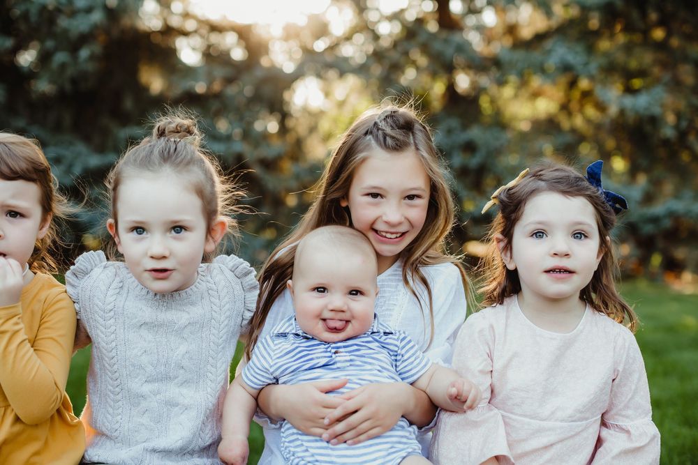 Group of young children sitting together outdoors during golden hour sunset.