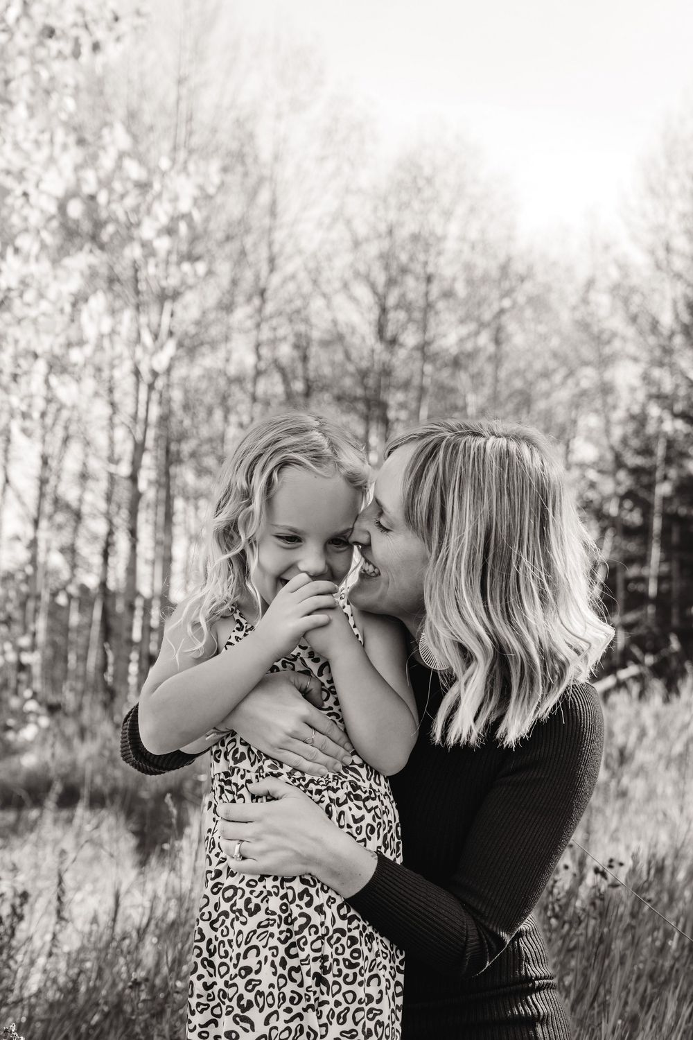 Black and white portrait of tender family moment in outdoor setting.