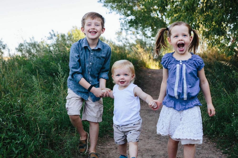 Children playing and running together on a dirt path surrounded by greenery.