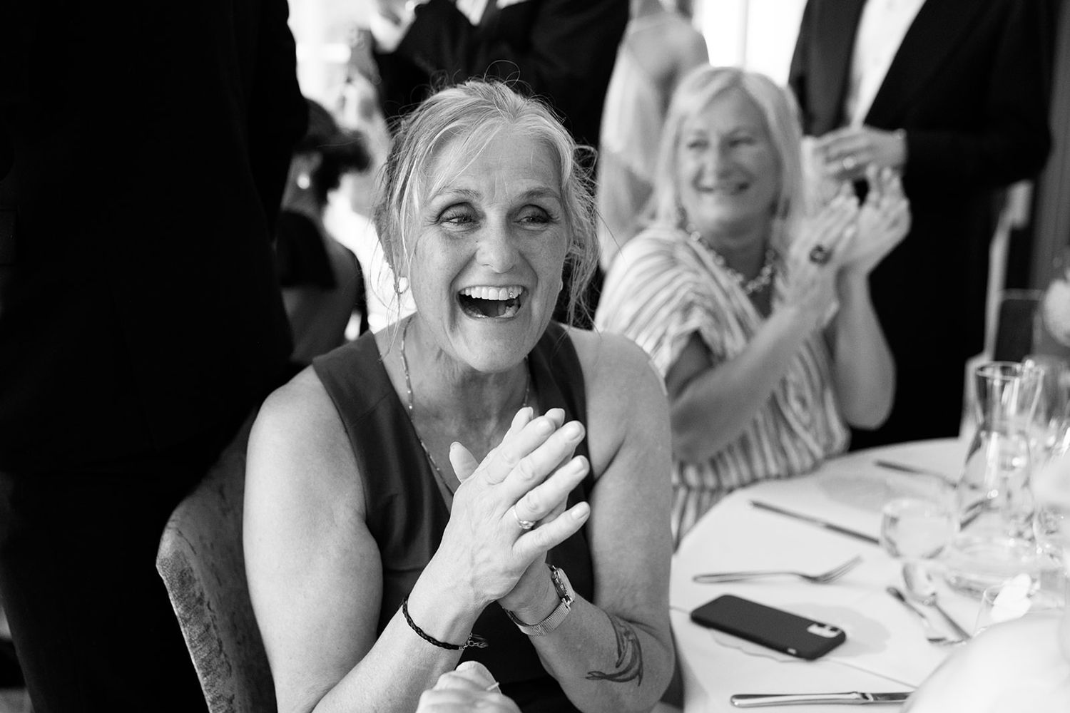 Group of wedding guests laughing and enjoying themselves at a reception dinner table.