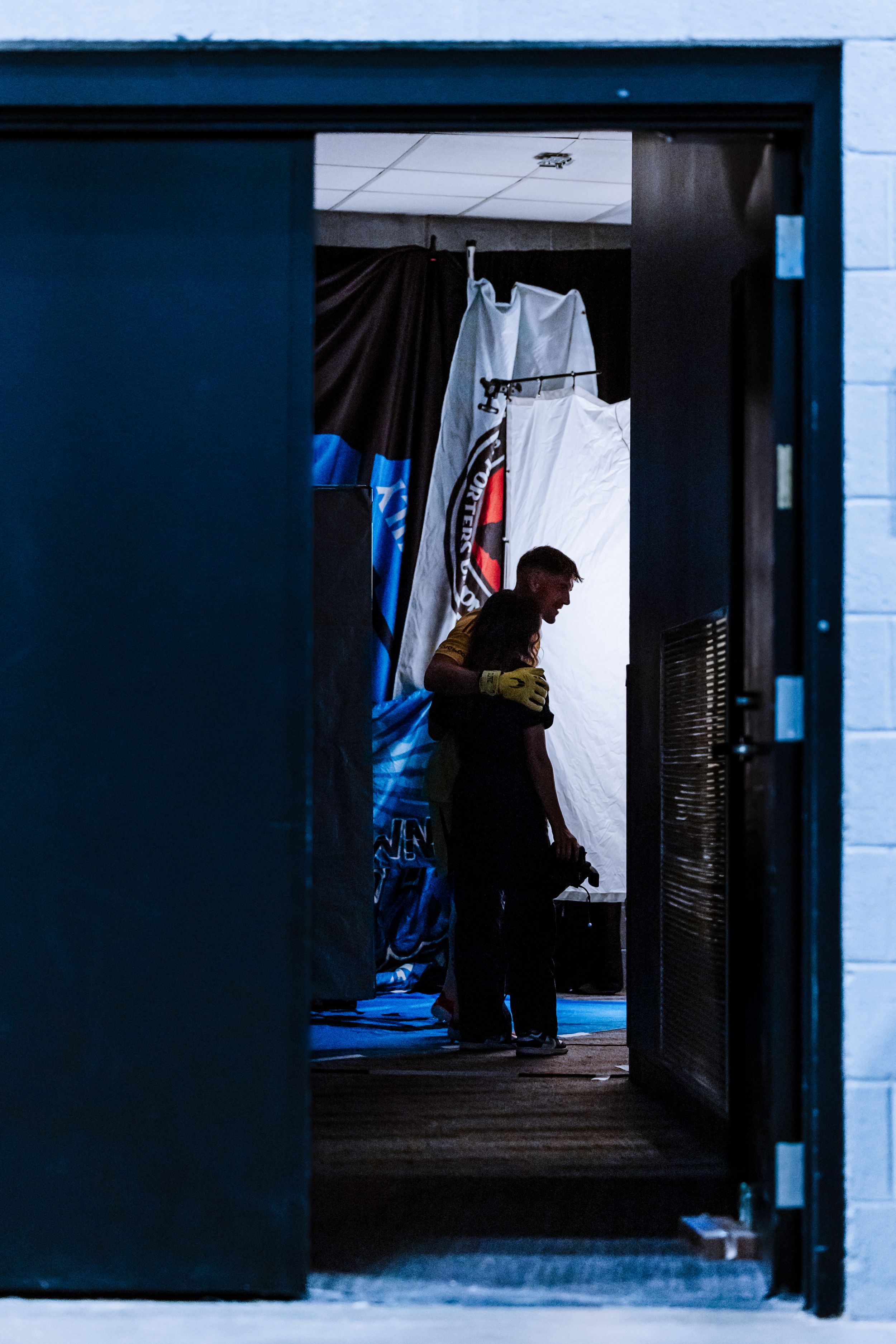 A photographer silhouetted in a doorway prepares a photo studio with Charlotte FC supporter flags.