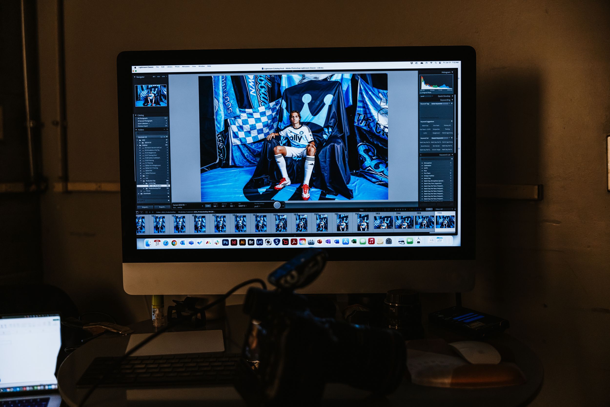 A photo editor reviews Charlotte FC player portraits on an iMac monitor in a dark editing studio.