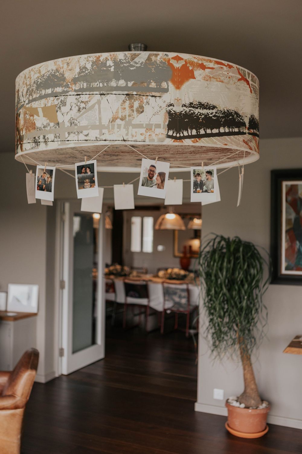 Rustic drum pendant light with hanging polaroid photos of couples in a warm home interior wedding venue.