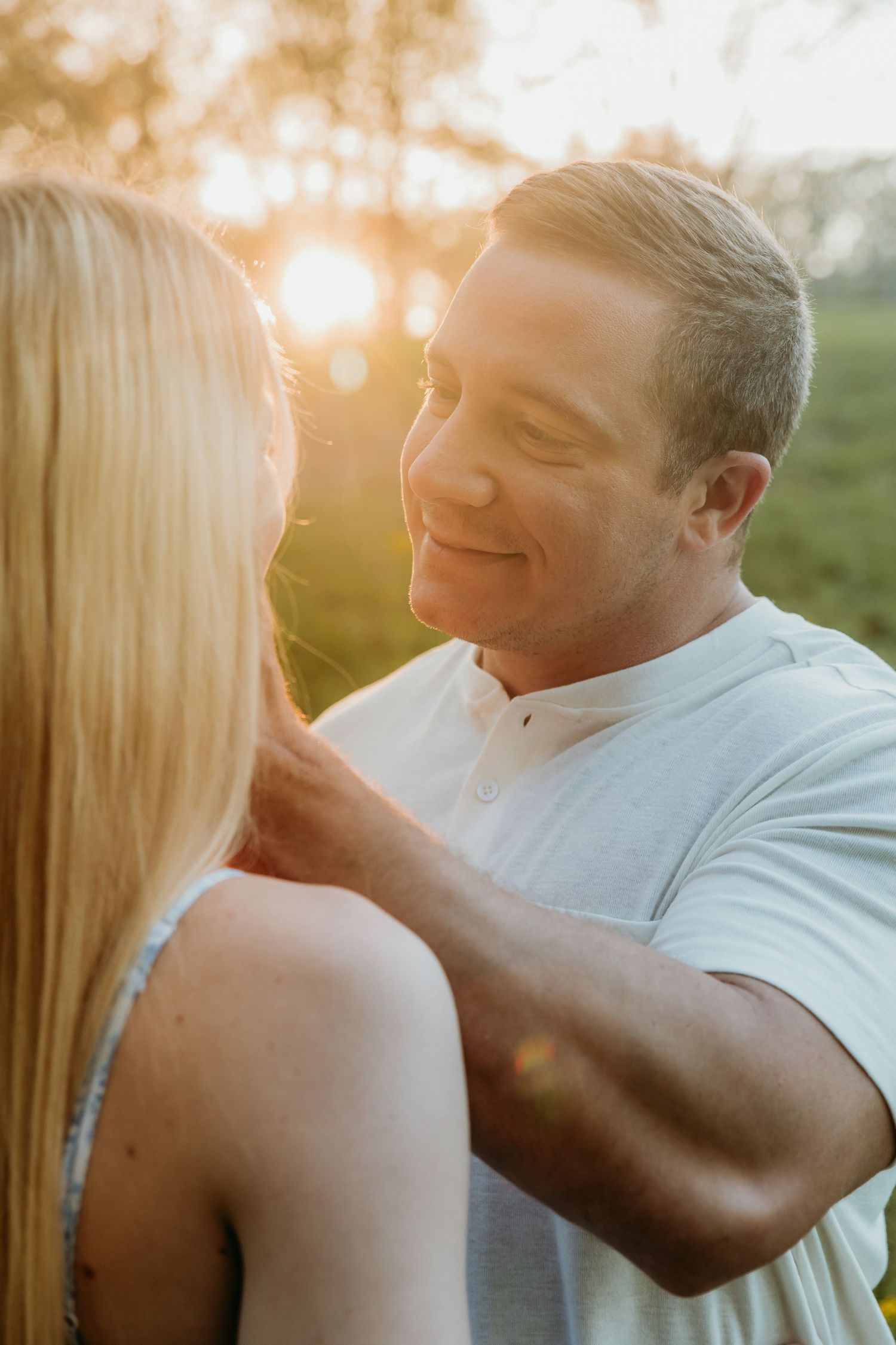 Intimate couple portrait bathed in warm sunset light against a natural outdoor setting.