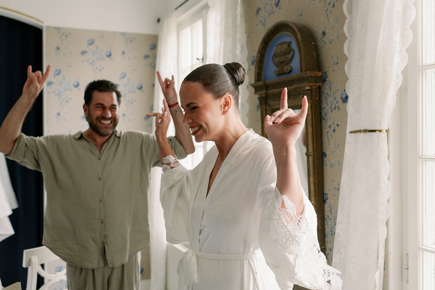 Wedding party members in white robes celebrating in a bright room.