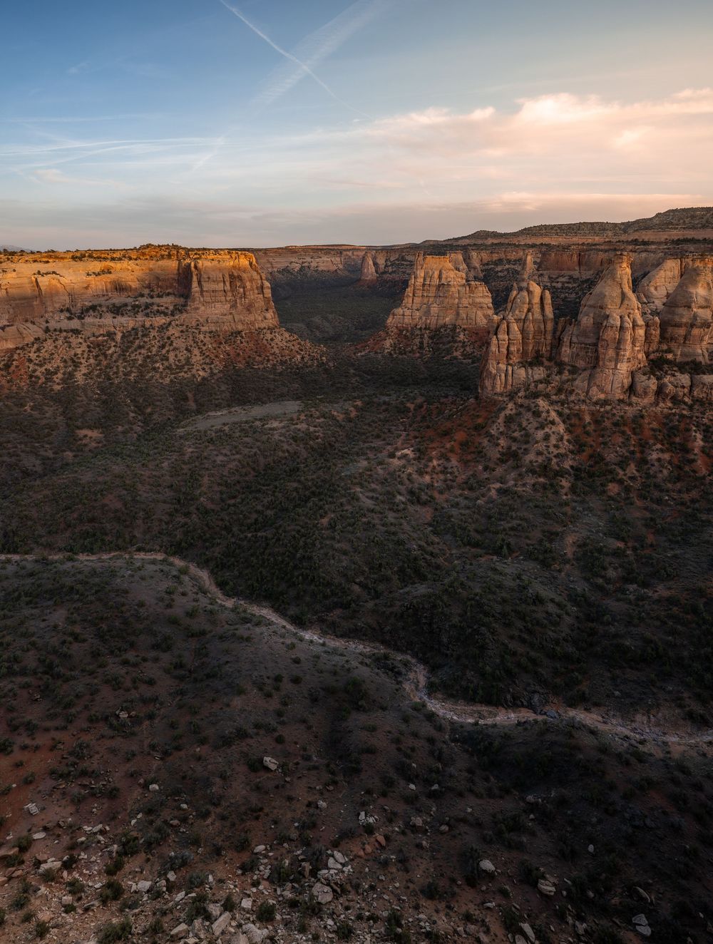 Aerial panoramic view of rugged desert canyon walls and cliffs at sunset in Colorado National Monument.
