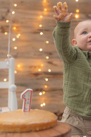 First birthday celebration with cake and string lights creating warm ambiance.