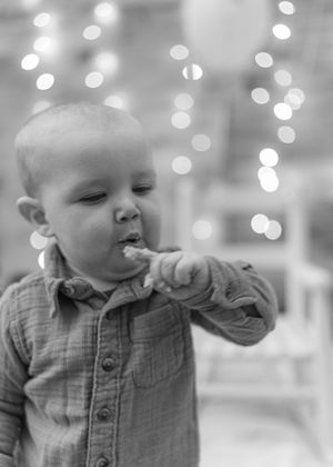 A sequence showing a baby in a plaid shirt making various facial expressions against a bokeh light background.