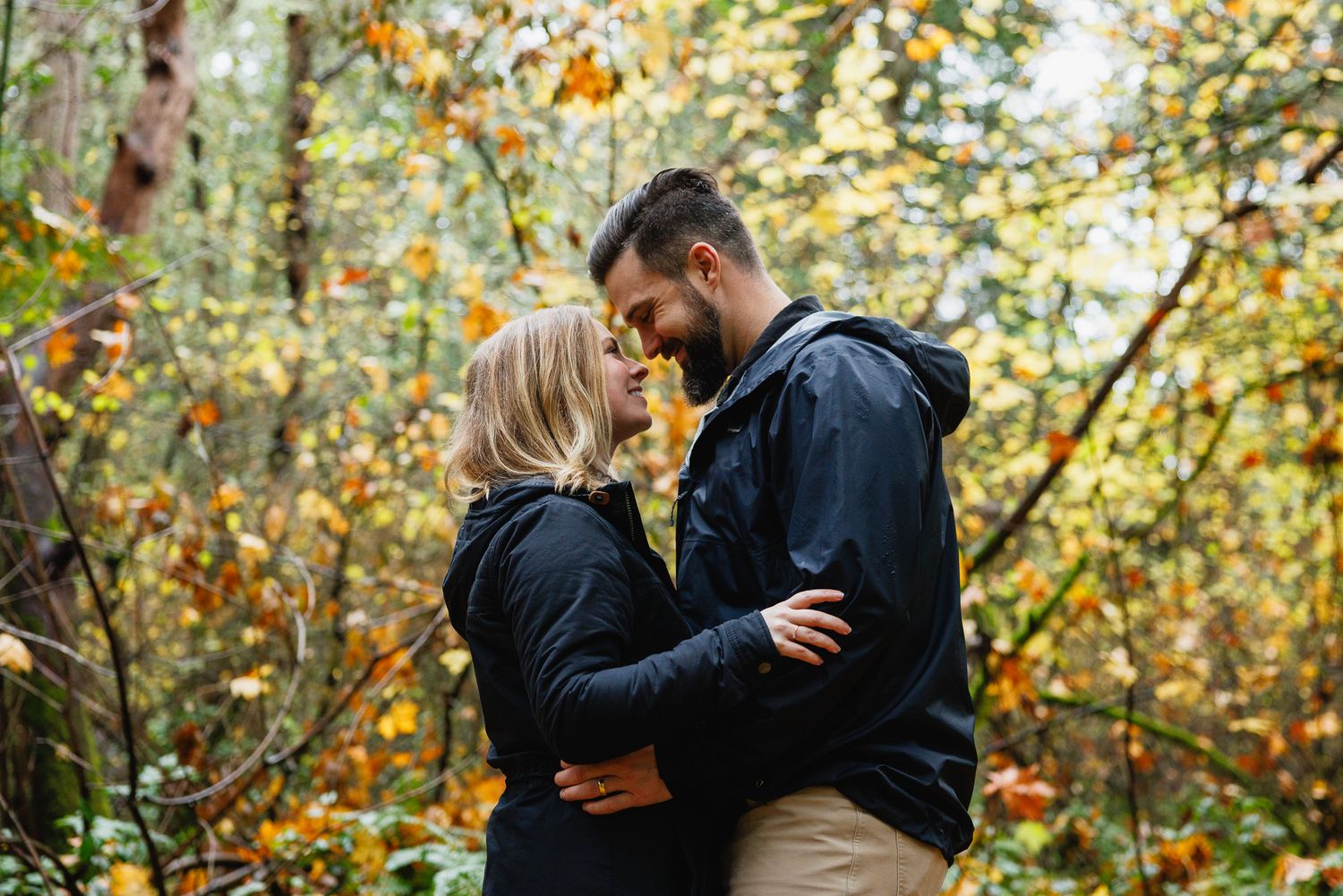 Couple sharing a romantic moment in an autumn forest surrounded by golden foliage.
