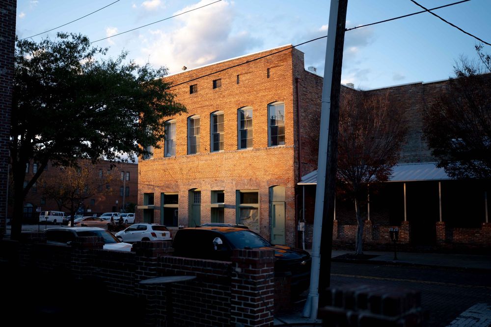 A panoramic view of brick commercial buildings with power lines against a cloudy sky.