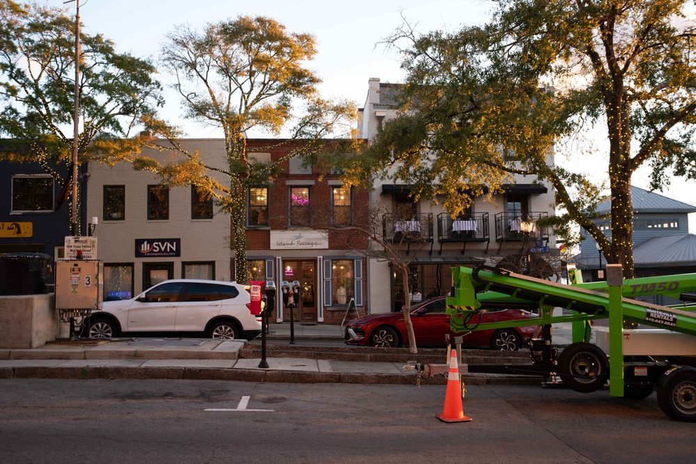 A panoramic view of a small town commercial street with brick buildings and autumn trees lining the sidewalk.
