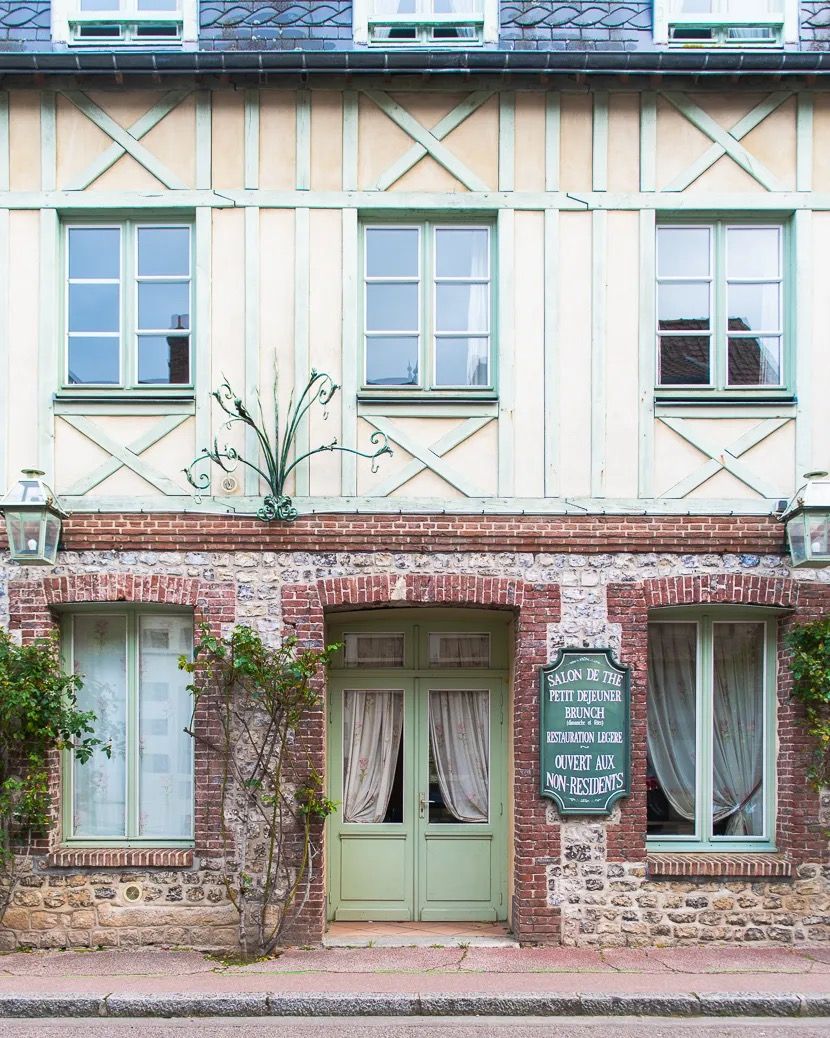 French townhouse with blue shutters, pink brickwork and a green door.