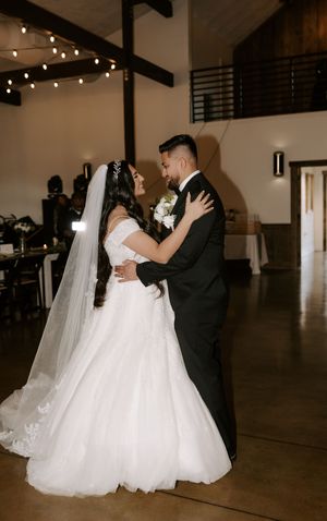 Wedding couple dancing in an elegant indoor venue with string lights overhead.