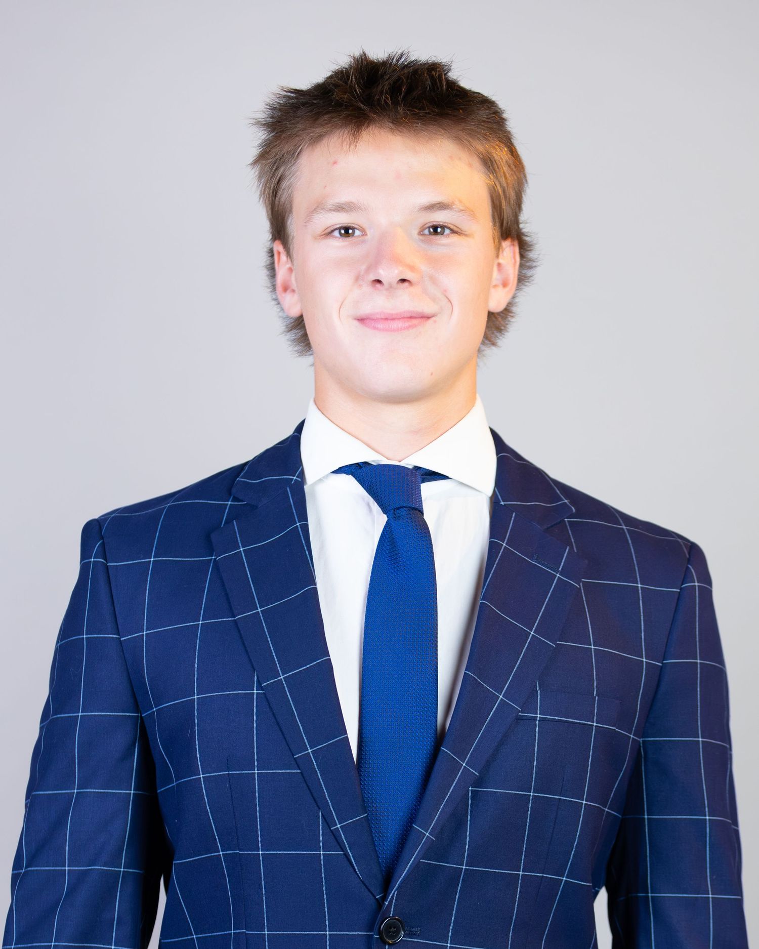A person wearing a navy windowpane suit with a blue tie and white shirt shown in multiple poses.