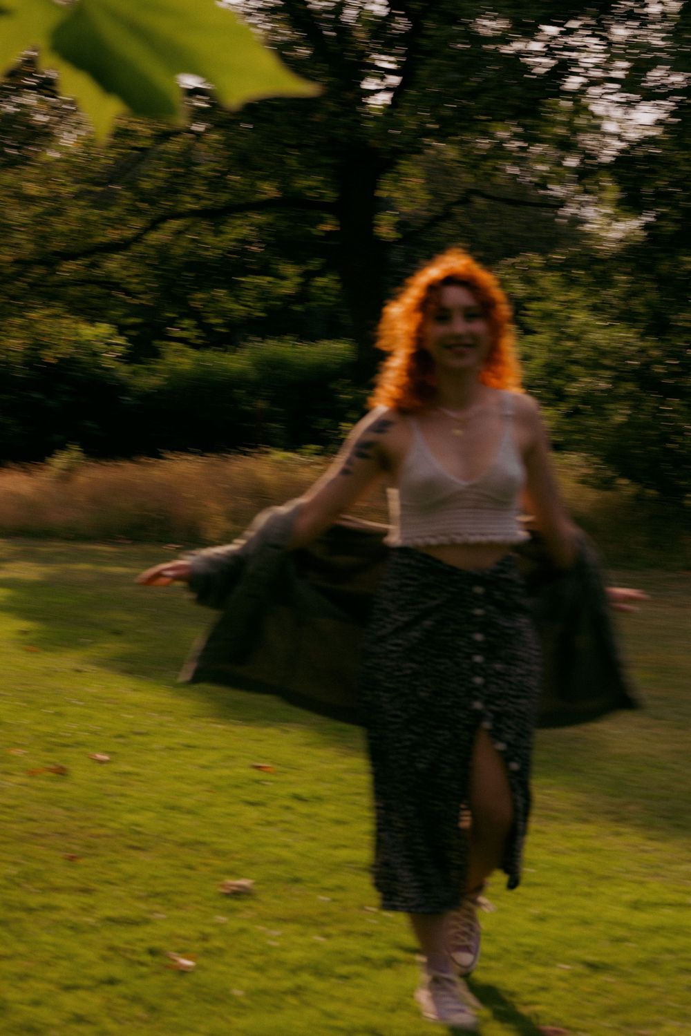 Figure dancing and twirling on green grass at sunset with motion blur effect.
