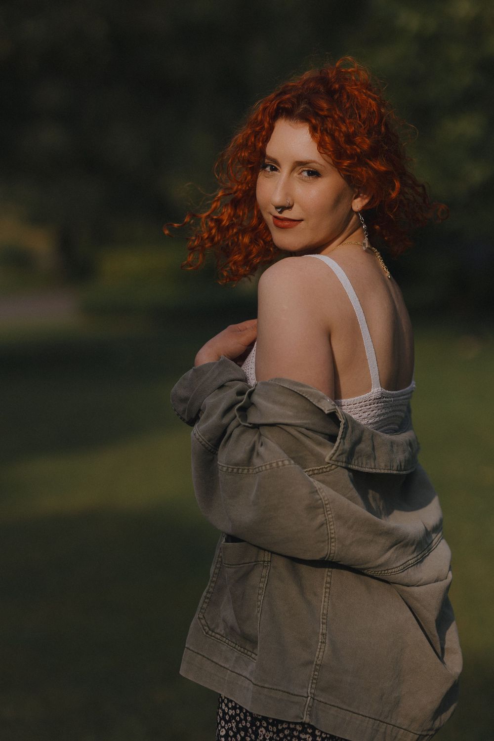 Artistic outdoor portrait showing someone in a denim jacket against a natural green background.