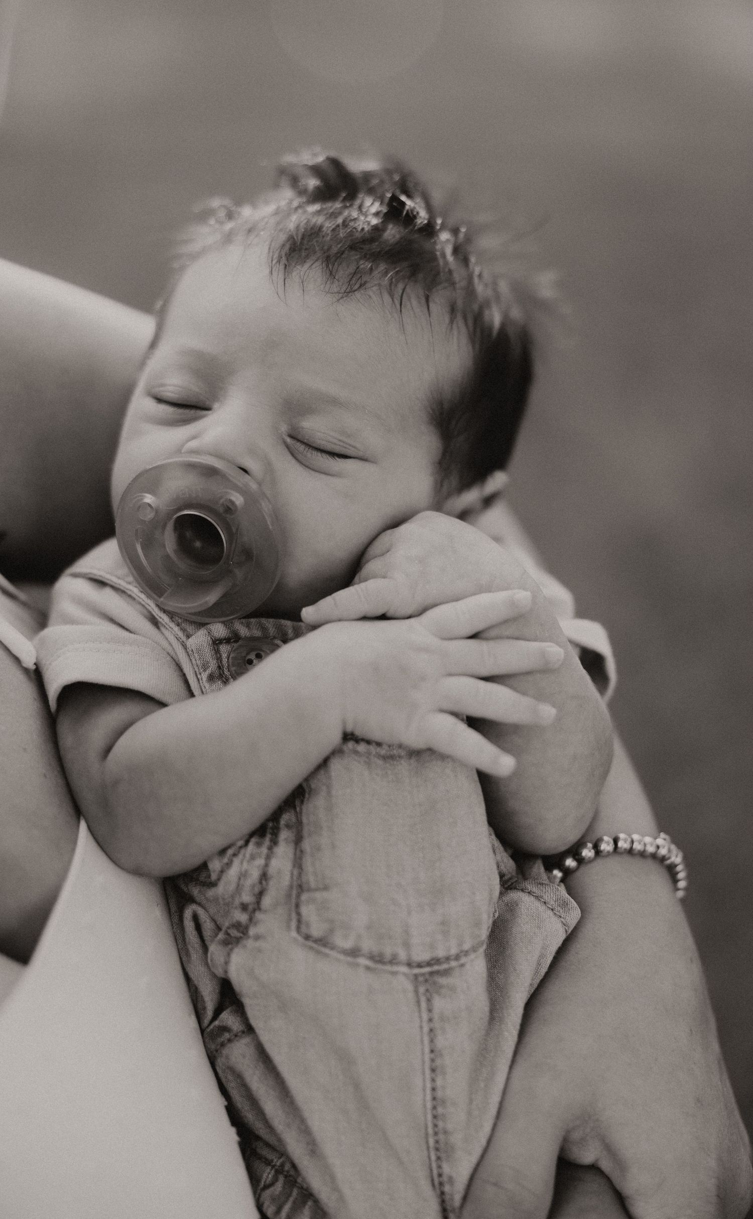 Black and white portrait series of a sleeping newborn being cradled with care.