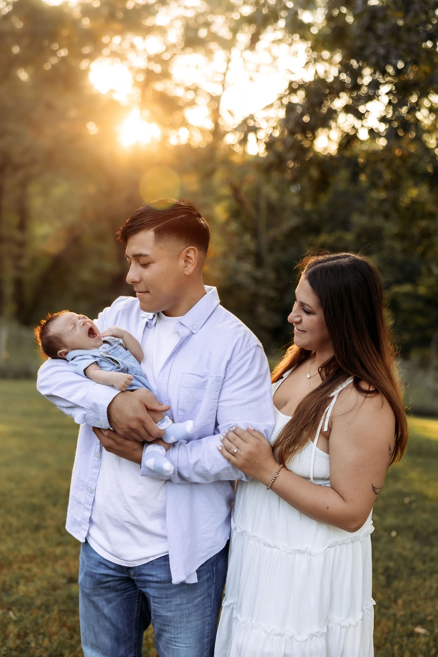 Family portrait session at sunset in a park with white and denim outfits.